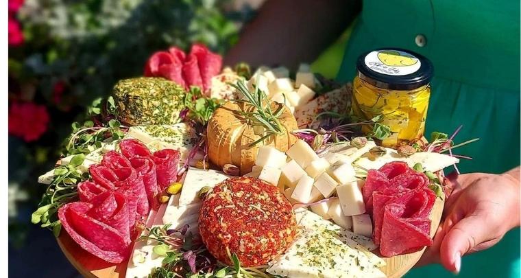 zdjęcie przedstawiające deskę z kawałkami serów i plastrami wędlin