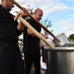 dwóch meżczyzn gotujacych rumpuć w kotle