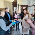 kobieta częstuje grupę osób sokiem jabłkowym