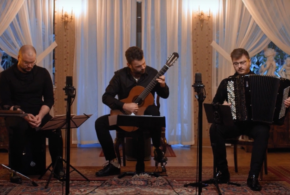 troje siedzących z instrumentami muzyków - perkusista gitarzysta i akordeonista