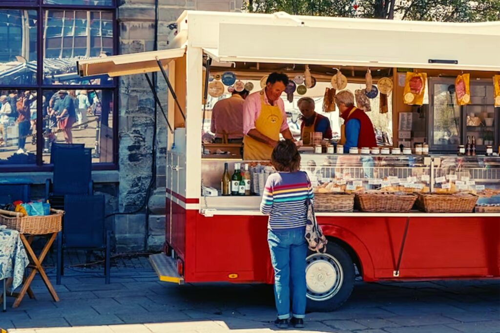 czerwono-biały foodtruck, mężczyzna serwujący jedzenie