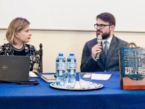 Mężczyzna i kobieta siedzący przy stole, prowadzący spotkanie