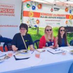 kilka osób siedzących przy stole pod namiotem w plenerze