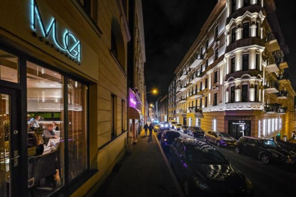 ulica miasta nocą, po lewej witryna restauracji o nazwie Muga